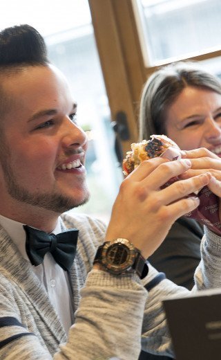 A young man is eating an juicy burger at the "Pöstli Corner" in Davos