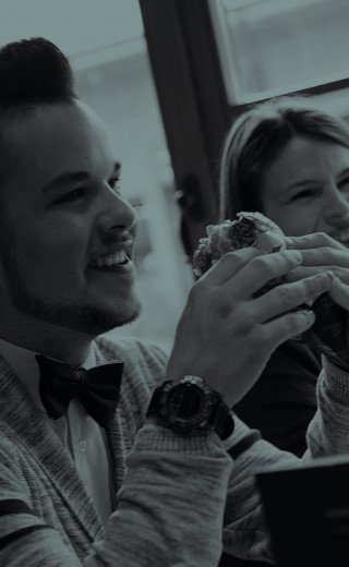 A young man is eating a juicy burger at "Pöstli Corner" in Davos